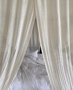 a bed with white sheets and curtains on top of it