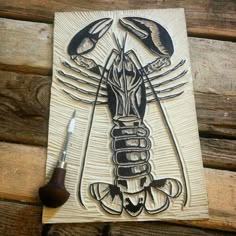 a wooden plaque with a drawing of a lobster on it's side next to a pair of scissors