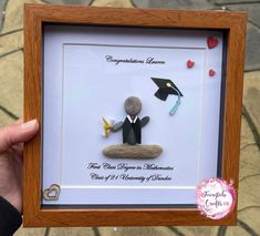 a person holding up a framed photo with graduation decorations