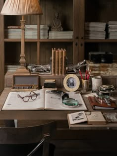 an open book sitting on top of a wooden desk next to a lamp and bookshelf