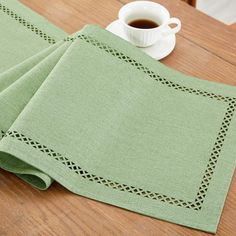 a cup of coffee sitting on top of a wooden table next to a green napkin