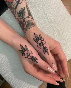 two women with matching tattoos on their hands holding each other's fingers and finger