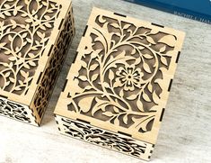 two wooden boxes sitting next to each other on top of a white table with a blue book in the background