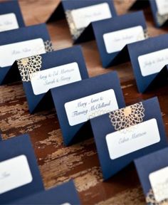 there are many place cards on top of the wooden table with blue and gold designs