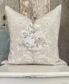 a white pillow sitting on top of a table next to a wooden wall with peeling paint