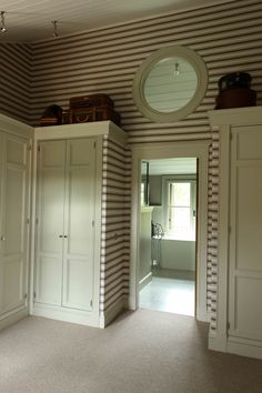 an empty room with striped walls and white cupboards on either side of the door