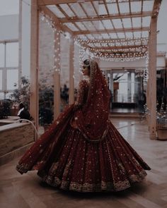 a woman in a red and gold bridal gown is looking down at the floor