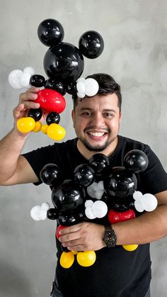 a man holding up mickey mouse balloons in front of his face