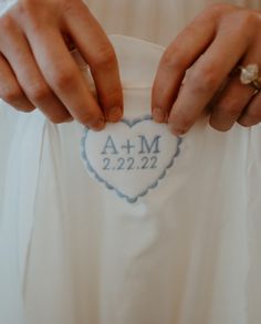 two hands holding onto a white shirt with a blue heart on the front and bottom