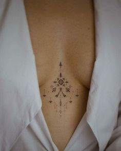 a woman's chest with an intricate tattoo design on her left side ribcage