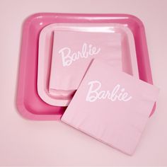 two pink plates with napkins that say barbie