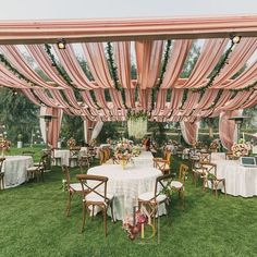 an outdoor wedding reception setup with pink draping and white linens on the ceiling