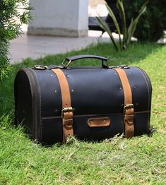 a black leather suitcase sitting in the grass