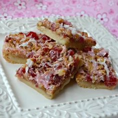 several pieces of dessert on a plate with pink and white lace table cloth behind it