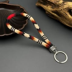 a beaded keychain with a metal ring on it next to a seashell