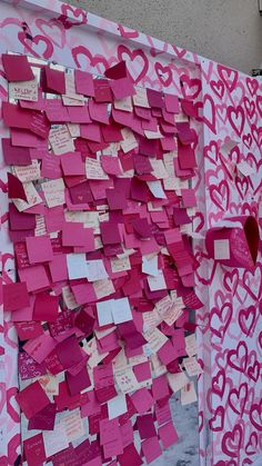 a wall covered in pink and white paper with lots of hearts attached to the side