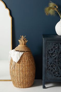 a white vase sitting on top of a wooden table next to a black cabinet and mirror