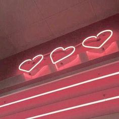 a neon sign that says love on the side of a building with three heart shaped lights