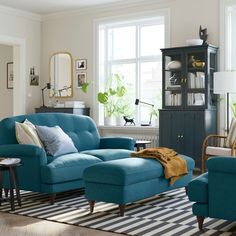 a living room with blue couches and chairs in front of a large open window