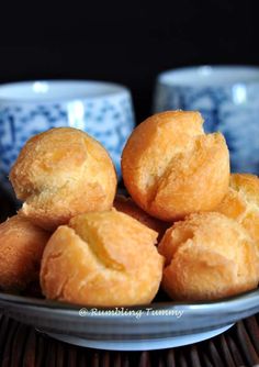 a white plate topped with doughnuts on top of a table next to cups