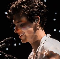 a man with curly hair singing into a microphone