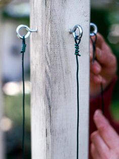 a person is holding two hooks on the side of a wooden pole with wires attached to it