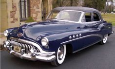 an old blue car parked in front of a building