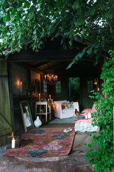 an outdoor area with lots of greenery and lights hanging from the ceiling, along with a rug on the floor