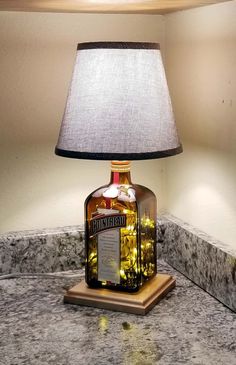 a bottle lamp sitting on top of a table next to a night stand with a light on it