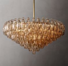 a chandelier made out of wine glasses hanging from a brass rod on a gray wall