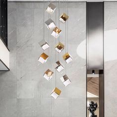 a modern chandelier hanging from the ceiling in a room with marble walls and flooring