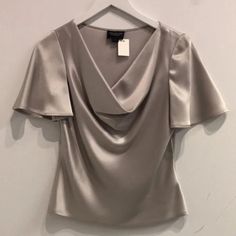 This Blouse From St. John’s Couture Line Is Made In A Grey Sumptuous Double-Faced Satin Full Of Luminous Shine, And Features Short Flared Sleeves, A Weighted Cowl Neckline, And Tonal Stitching. Condition: Great; Moderate Spotting, Light Snagging. Size: 2 Approximate Measurements: Shoulder: 14.75" (37.5 Cm) Chest: 17.75" (45 Cm) Length From Back: 21" (53 Cm) Sleeve Length: 9.75" (25 Cm) Composition: 78% Triacetate, 22% Polyester. Sleek Satin Blouse With Button Closure, Semi-formal Satin Button-up Blouse, Semi-formal Satin Top With Button Closure, Elegant Satin Tie-neck Blouse, Satin Tunic, Luxury Satin Button-up Blouse, Liquid Satin, John Gray, Satin Blouses