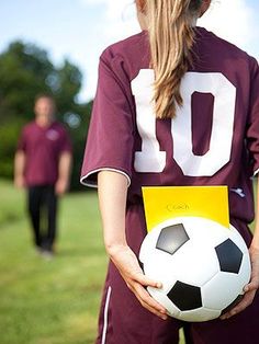 a girl holding a soccer ball in her hands with another person behind her on the other side