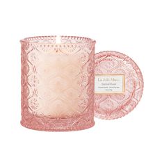 a pink glass candle next to a plate