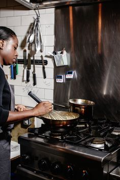 a woman is cooking in the kitchen with a frying pan on the stove