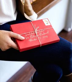 a woman holding a red gift box with writing on it