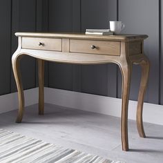 a wooden table sitting in front of a window with a cup on top of it