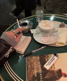 a person sitting at a table with a cup of coffee and some books on it