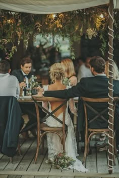 a bride and groom sitting at a table with their guests