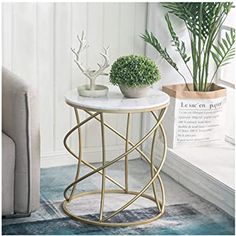 a white marble top side table with gold metal frame and planters on the end