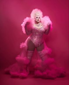 a woman dressed in pink is posing with feathers on her head and body, while she wears