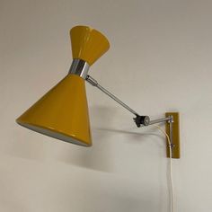 Herda wall lamp in the shape of a diabolo from the 1970s. The maximum adjustable length is 65 cm. The height is 26 cm and diameter of the shade (at the bottom) is 18 cm. This vintage ellbow wall lamp is fully adjustable (see photos). The condition is still very good and original; the wiring has been checked by an electrician. Material: metal, chromed metal and aluminium. Colour: yellow and silver. Dimensions adjustable: h x w x d = 26 x 18 x 26-65 cm. Diameter shade: 18, height shade 26. I have Wall Mounted Lamp, Vintage Wall Lamp, Mounted Lamp, Wall Mounted Lamps, Colour Yellow, The Shade, The 1970s, Live Light, To Do