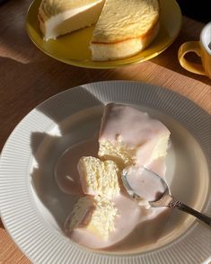 a plate with some cake on it next to a cup of coffee and a spoon