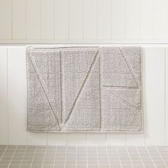 a towel hanging on the wall next to a tiled floor in a room with white walls