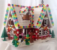 a building made out of legos on a white surface with christmas decorations around it