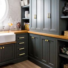 a kitchen with gray cabinets and wooden counter tops, gold handles on the sink drawers