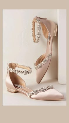 a pair of pink high heeled shoes next to a white wall with a diamond - embellished shoe