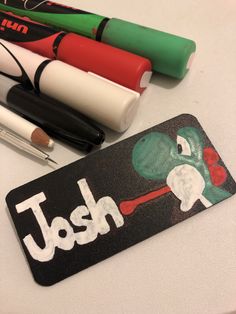 pens and markers sitting on top of a desk next to a name tag with the word jash written on it