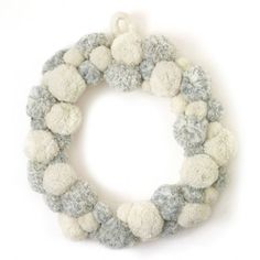 a white and gray wreath with pom - poms hanging from the front, on a white background