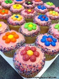 cupcakes with pink frosting and multi colored candies on top are sitting on a white plate